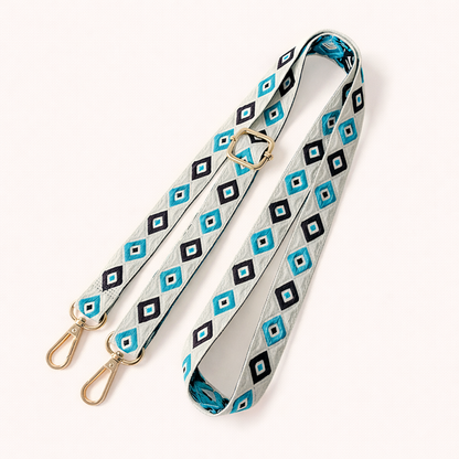 Woven Jetlag long phone strap in blue, black, and white diamond pattern, coiled flat with gold clasps.