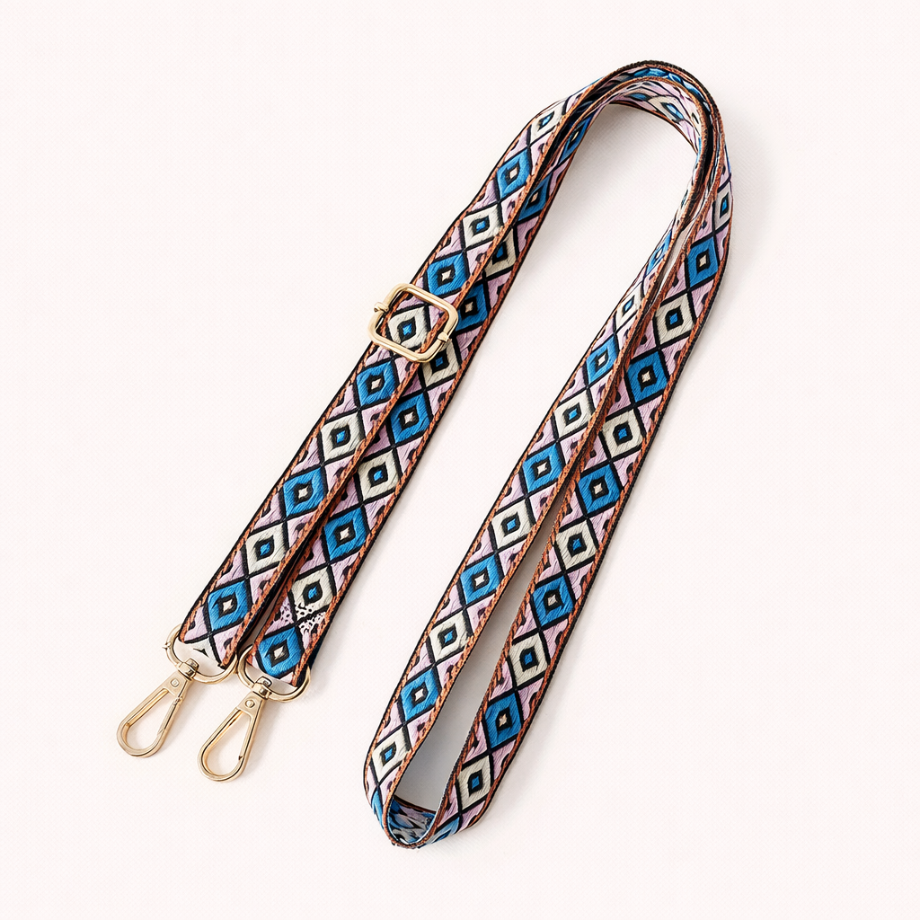 Woven Jetlag long phone strap in blue, pink, and tan diamond pattern, coiled flat with gold clasps.