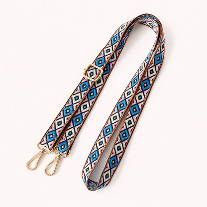 Woven Jetlag long phone strap in blue, pink, and tan diamond pattern, coiled flat with gold clasps.