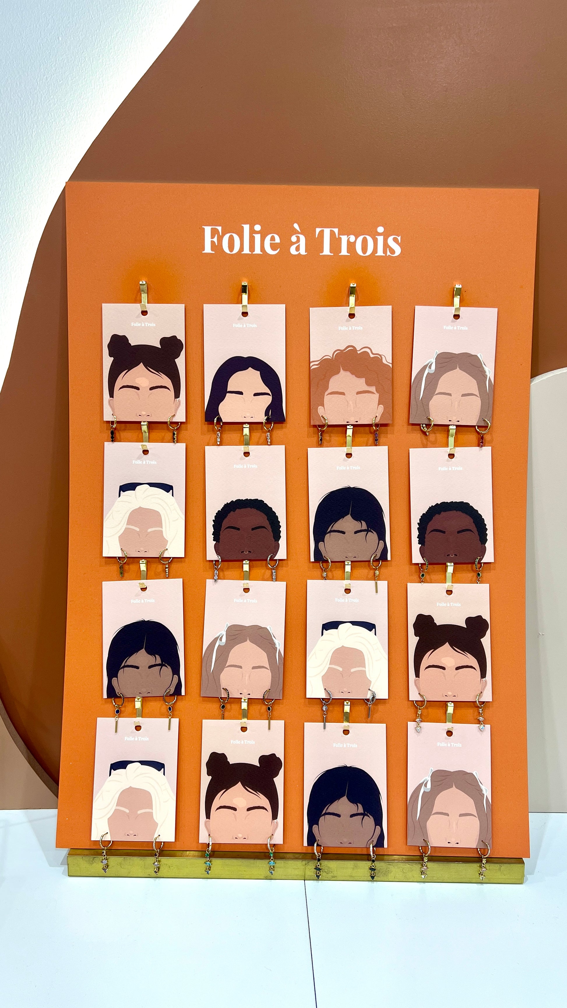 Terracotta jewelry board fully hung with sixteen illustrated face cards each displaying a different earring style.