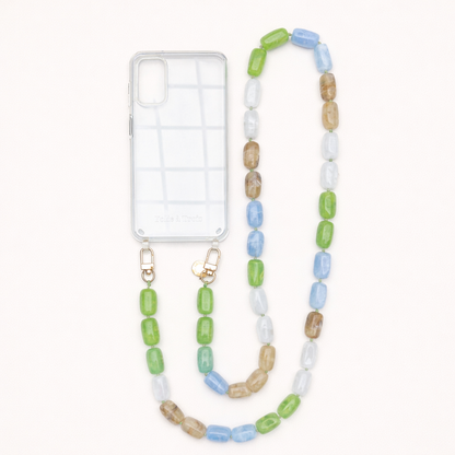 A clear phone case with a green, blue, tan, and white bead phone chain, shown on a cream background.