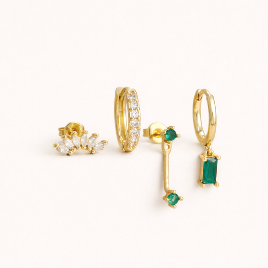 Juna Set of four gold pieces: a marquise crystal crawler stud, a pave hoop, an emerald-dot bar stud, and an emerald baguette hoop.