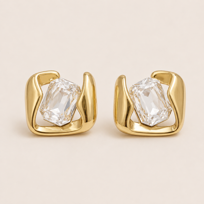 Gold sculptural stud earrings gripping a large emerald-cut white stone in a swirled open frame — Folie à Trois Kaleidoscope EARRINGS