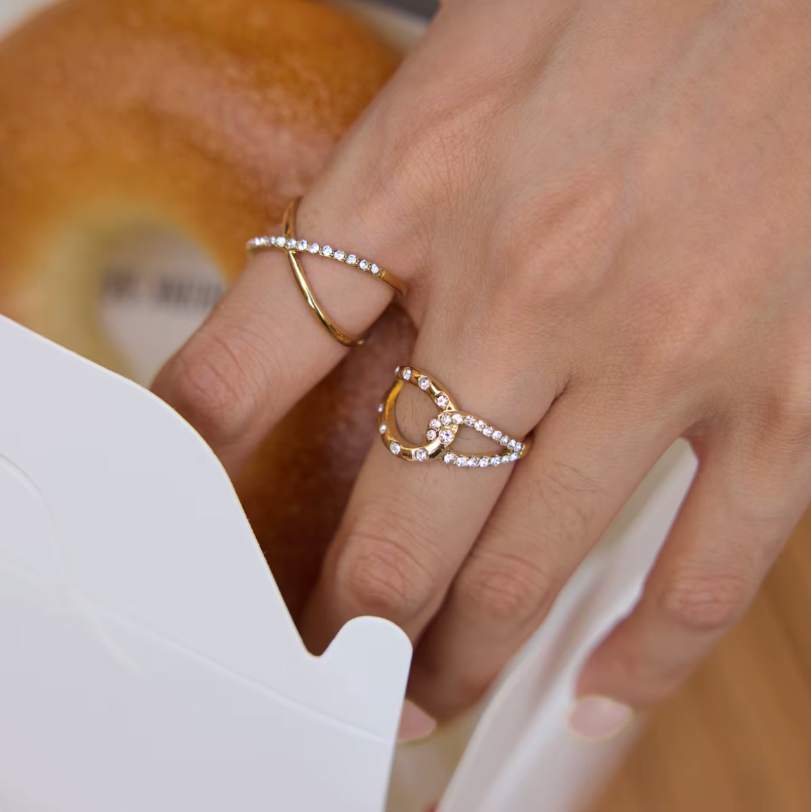 Model wears the Kalimera RING stacked with a teardrop pavé ring while reaching into a white takeout box.