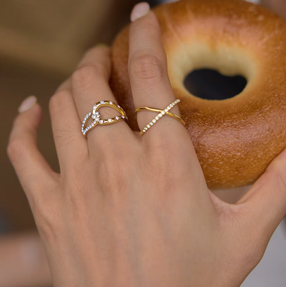 Model wears the Kalimera RING stacked with a pavé teardrop ring while holding a bagel.