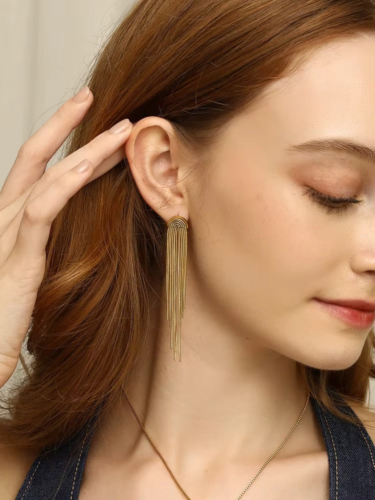 Kiss and Tell Earring worn on the ear in gold, the chain fringe cascading down beside loose flowing hair.