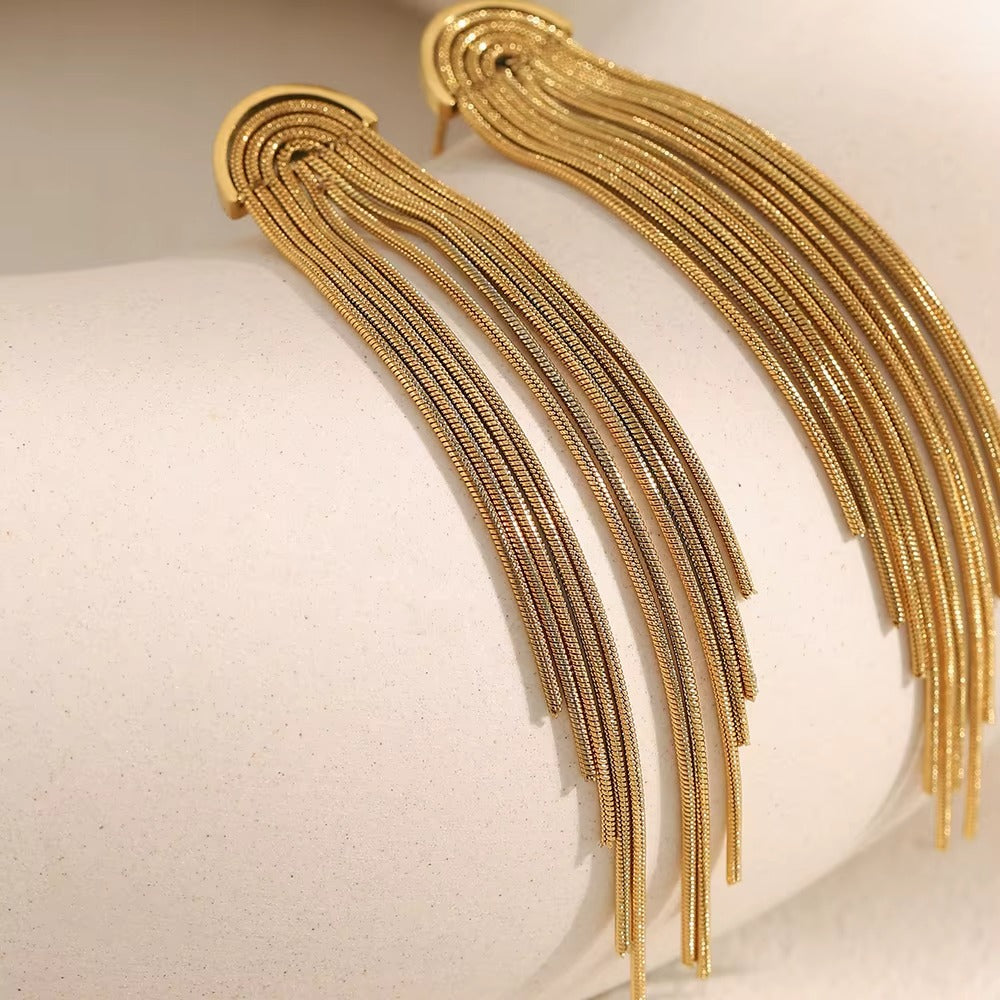 Kiss and Tell Earrings in gold draped over a curved white stone, the long chain fringe catching the light.
