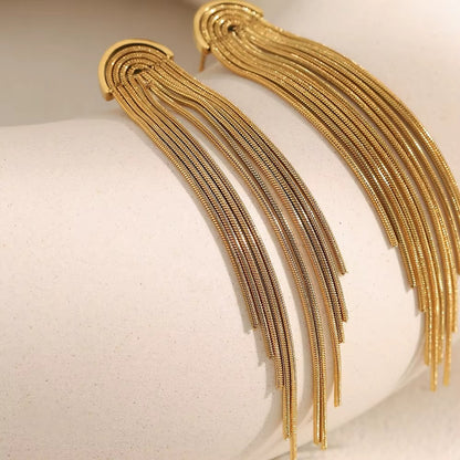 Kiss and Tell Earrings in gold draped over a curved white stone, the long chain fringe catching the light.