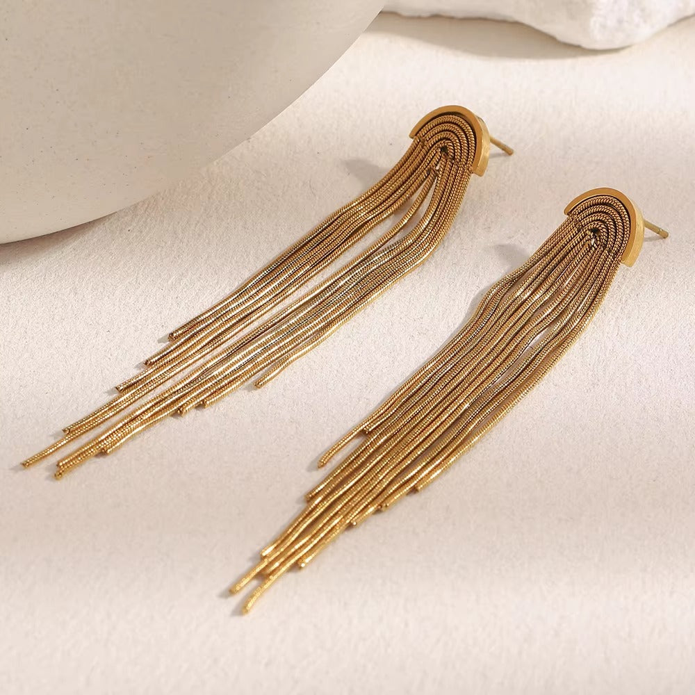Kiss and Tell Earrings in gold on a textured stone surface, showing the cascading snake chain fringe.