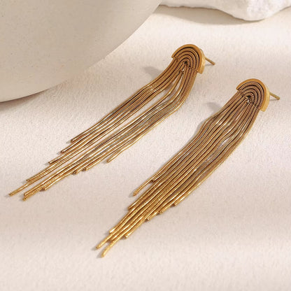 Kiss and Tell Earrings in gold on a textured stone surface, showing the cascading snake chain fringe.