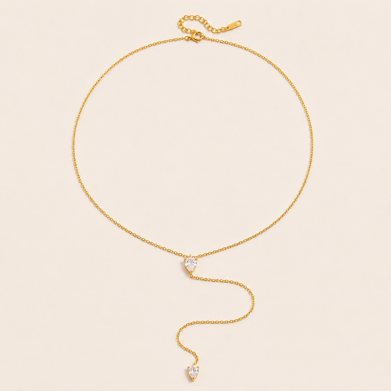 Gold Lariat Y NECKLACE with two pear-shaped crystal accents on a fine chain, drawn into a long drop, laid flat.