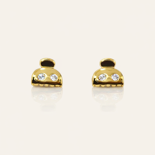 Lay It On Me Earrings take the shape of tiny gold handbags, each set with two round clear stones and a fringed base.
