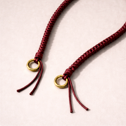 Burgundy braided Layover long phone strap, close-up of the knotted gold ring and fringe end.