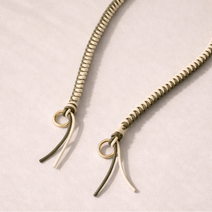 White and olive two-tone braided Layover strap, close-up of the knotted gold ring and fringe end.