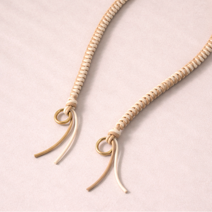 Cream braided Layover long phone strap, close-up of the knotted gold ring and fringe end.