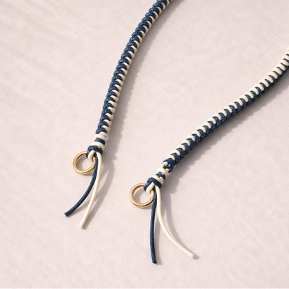 Navy and white two-tone braided Layover strap, close-up of the knotted gold ring and fringe end.