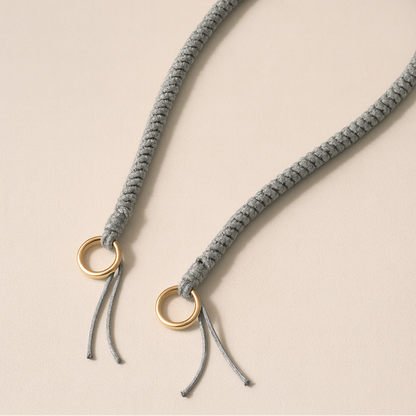 Solid gray braided Layover long phone strap, close-up of the knotted gold ring and fringe end.