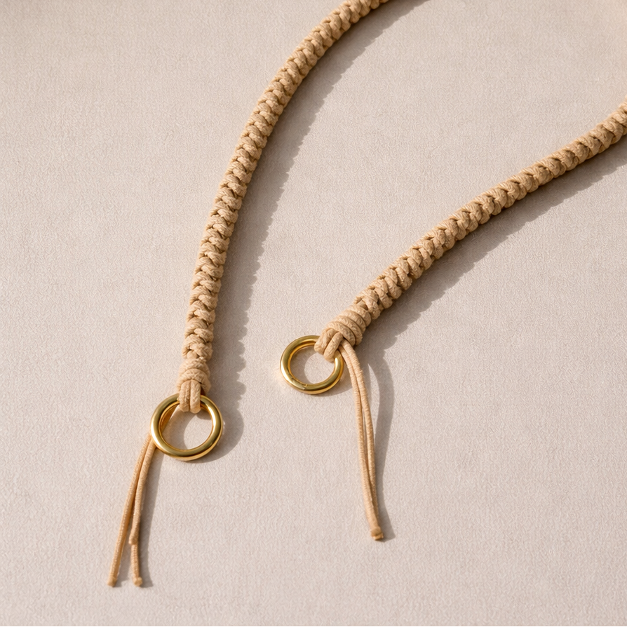 Tan braided Layover long phone strap, close-up of the knotted gold ring and fringe end.