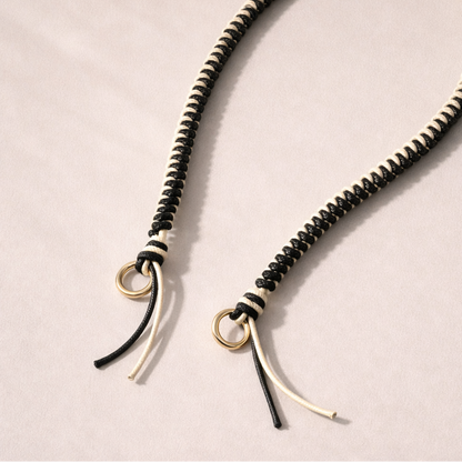 Black and white two-tone braided Layover strap, close-up of the knotted gold ring and fringe end.