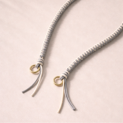 Gray and white two-tone braided Layover strap, close-up of the knotted gold ring and fringe end.