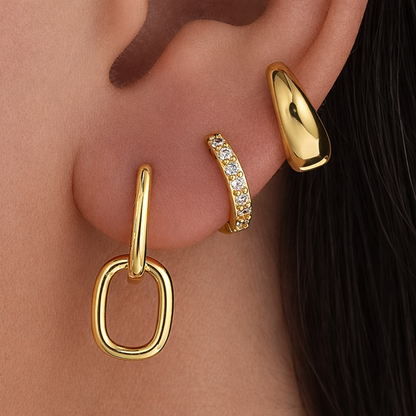 Lea Set worn on the ear in gold, a paperclip charm hoop and pave hoop stacked beside a chunky teardrop stud.