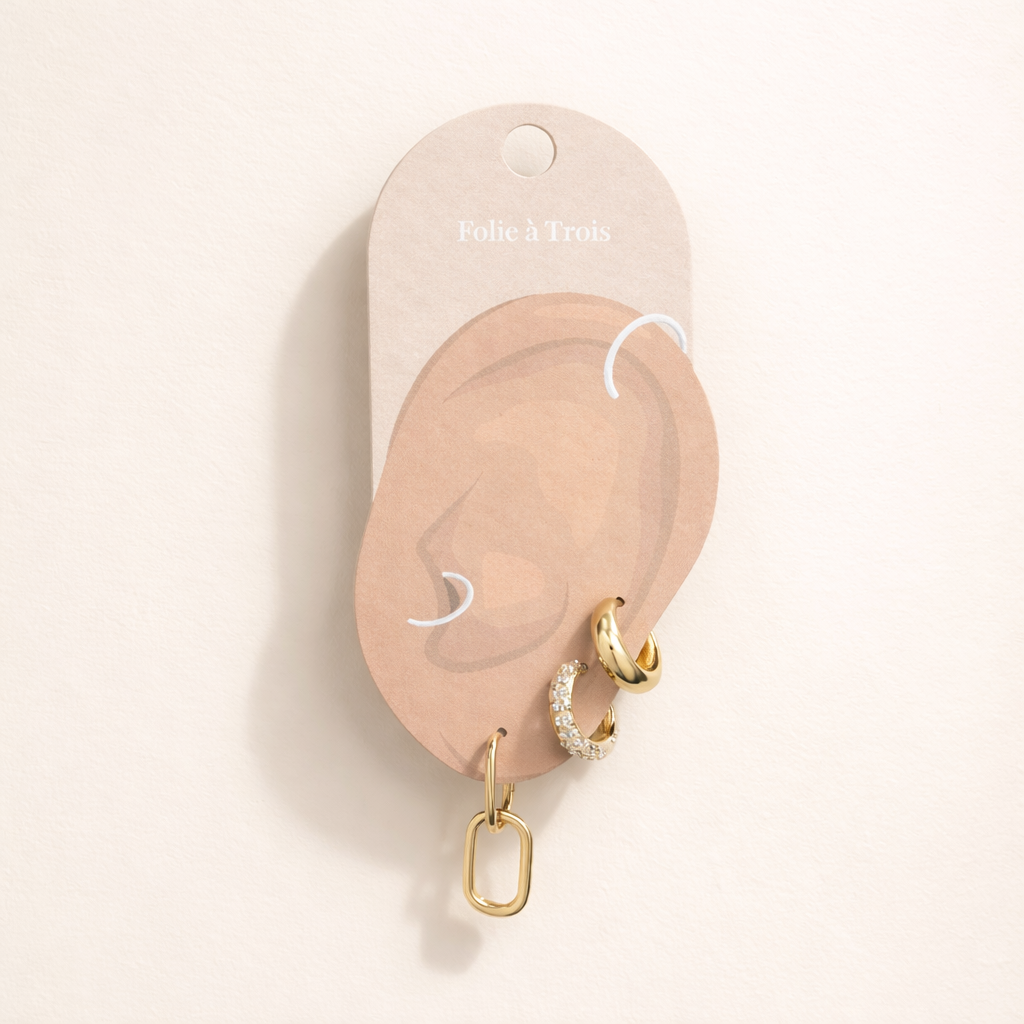 Lea Set displayed on a Folie a Trois ear-shaped card in gold, arranging the pave hoop and paperclip charm hoop for styling.