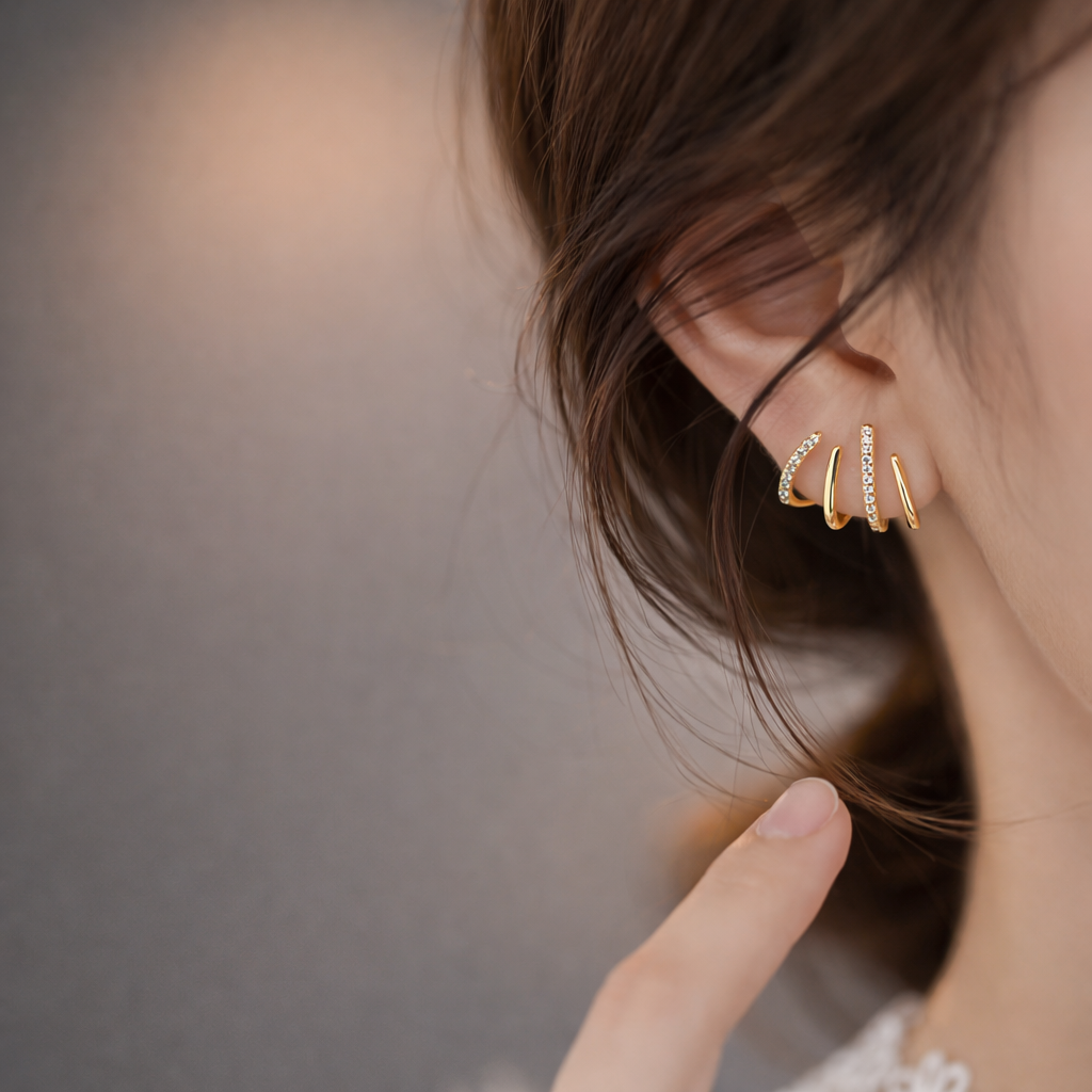 Worn on a model's ear, the gold Lennon EARRINGS show their three curved, pave-lined bands in close-up.