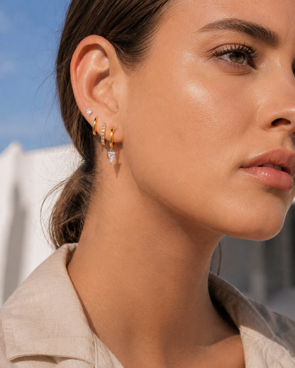 Lexi Set worn close on the ear in gold, a diamond-shaped stud beside a plain hoop, pave hoop, and triangle crystal drop hoop.