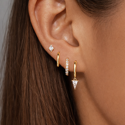 Lexi Set worn close on the ear in gold, a diamond-shaped stud above hoops and a dangling triangle crystal drop.
