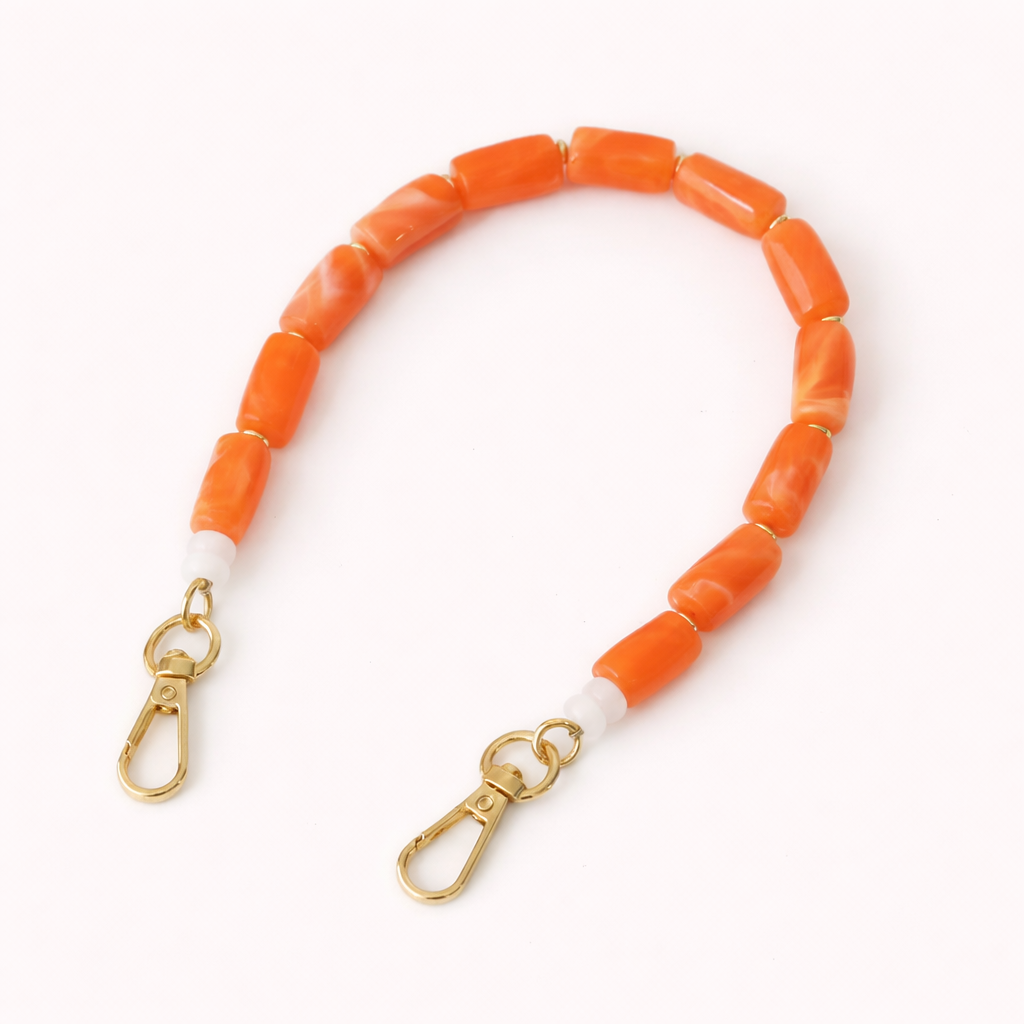 Coral orange beaded Lilette short phone strap coiled flat with gold-tone clasp ends.