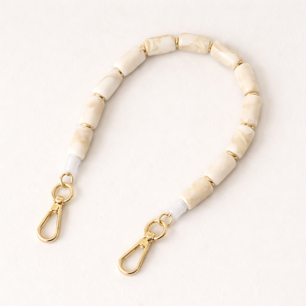 Ivory marbled beaded Lilette short phone strap coiled flat with gold-tone clasp ends.