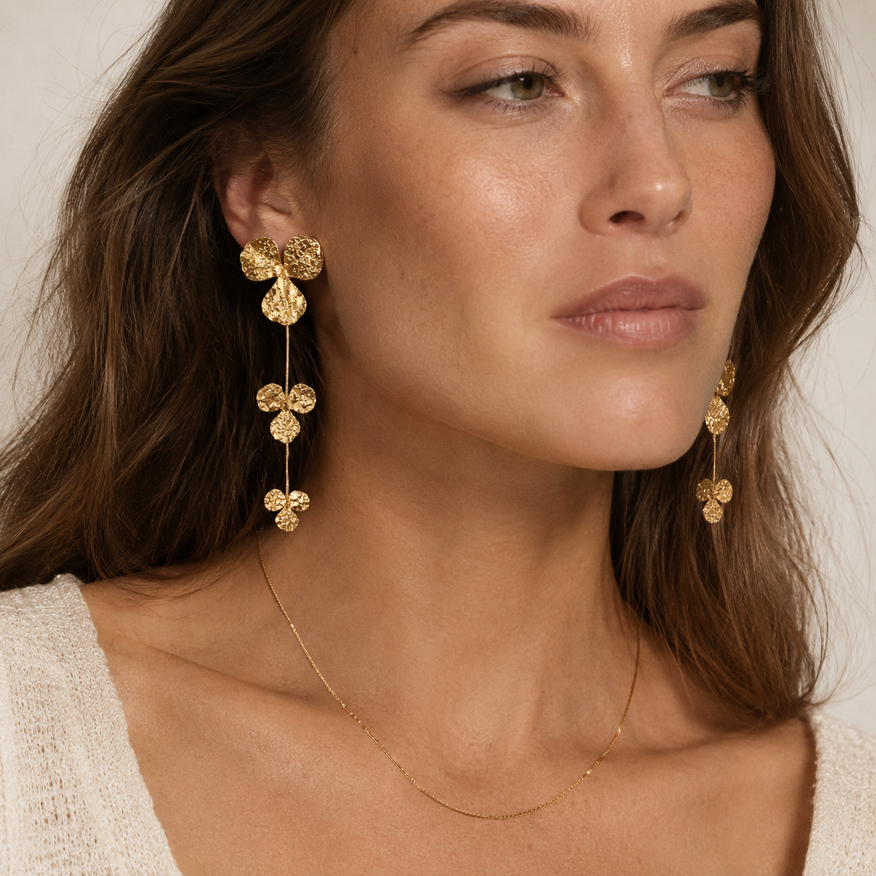 Model wears the Folie à Trois Litoral EARRINGS, a cascading gold trefoil drop earring, layered with a fine chain necklace.