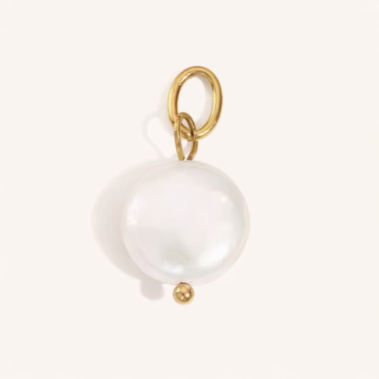 The Little Pearl CHARM in a flat lay, a round coin pearl on a gold paperclip connector with a small gold bead, cream background.