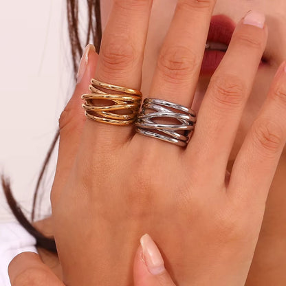 Close-up of a hand stacked with the gold and silver wrap-style Lizie RING pieces worn together on one finger.