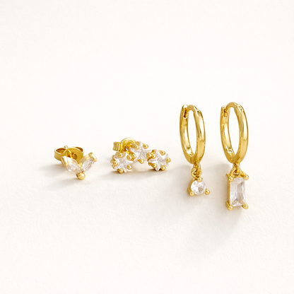 Lola Set of four gold pieces: a marquise crystal stud, a trio flower-cluster stud, and two hoops with round and baguette crystal drops.