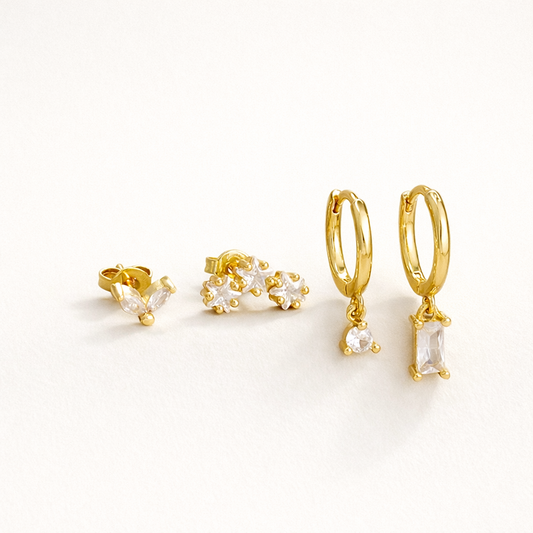 Lola Set of four gold pieces: a marquise crystal stud, a trio flower-cluster stud, and two hoops with round and baguette crystal drops.