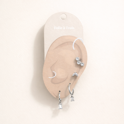 Lola Set displayed on a Folie a Trois ear-shaped card in silver tone, arranging the studs and crystal-drop hoops for styling.
