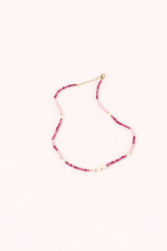 The Lolita NECKLACE, a beaded strand of pink and burgundy gemstones interspersed with small pearls, shown flat.
