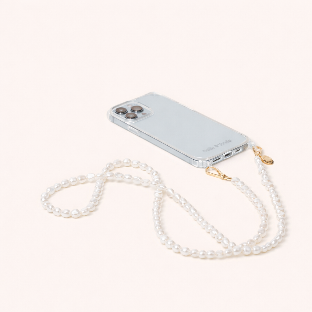 Clear phone case attached to a long strand of small round pearls, the Long Pearl PHONE STRAP shown on a cream background.