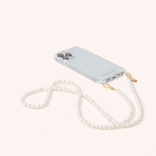 Clear phone case attached to a long strand of small round pearls, the Long Pearl PHONE STRAP shown on a cream background.