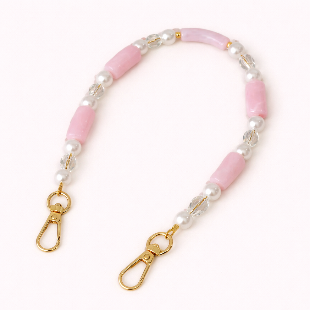 Pink beaded Loreto short phone strap coiled flat, accented with pearls, crystals, and gold-tone clasps.