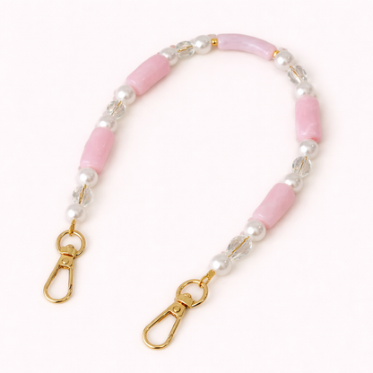 Pink beaded Loreto short phone strap coiled flat, accented with pearls, crystals, and gold-tone clasps.