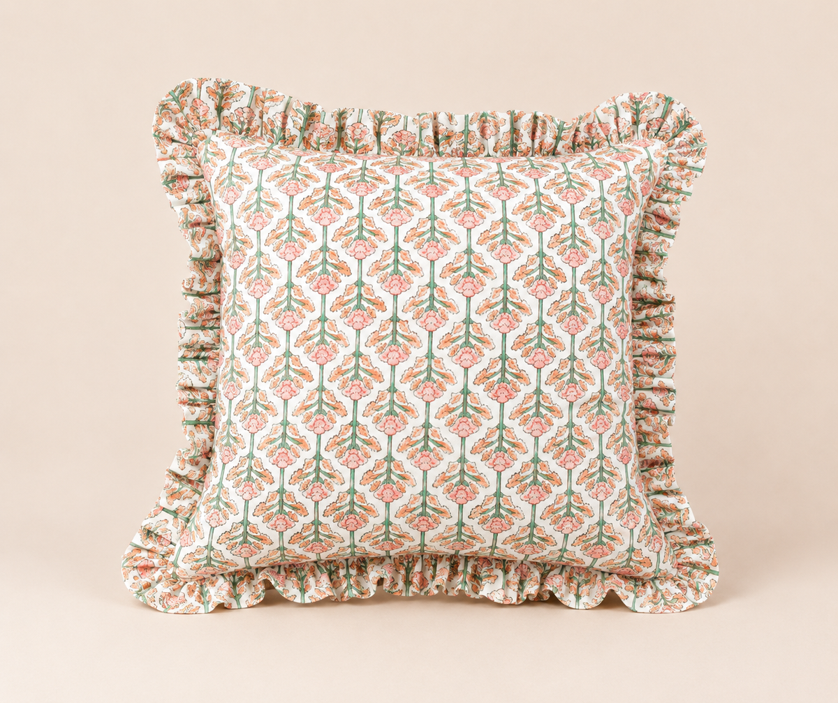 Front view of the Lotus Pink Square cushion with a pink and green floral block-print pattern and a soft ruffled edge on a beige background.