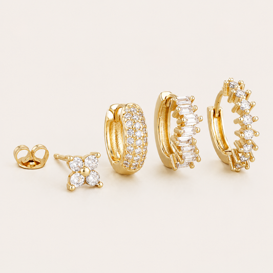 Four-piece Lou SET gold earrings: a four-stone flower stud, a pave hoop, a baguette-stone hoop, and a hoop with round stones.