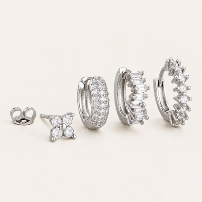 The Folie à Trois Lou SET in silver: a four-stone flower stud, a pavé hoop, a baguette-stone hoop and a round-stone hoop.