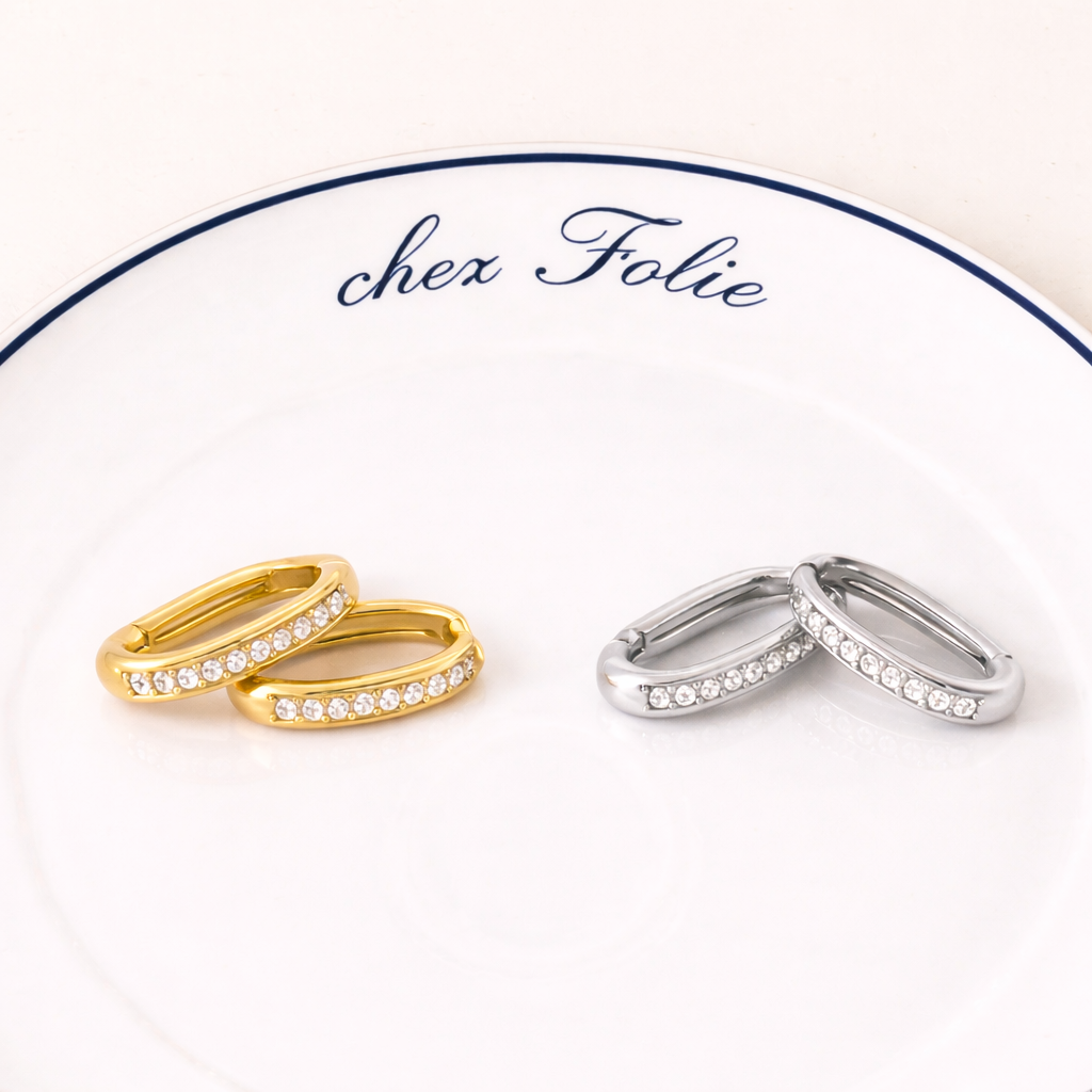 Gold and silver Love Bite EARRINGS rest on a branded plate, each pair lined with sparkling crystals.