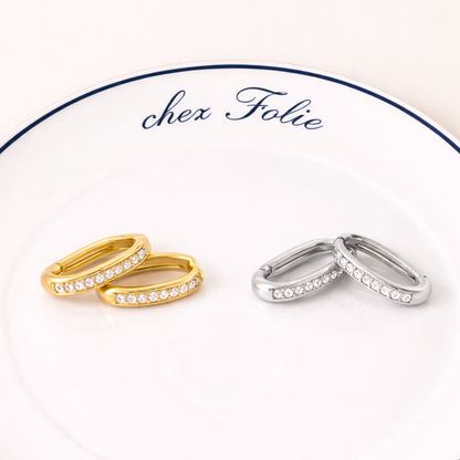 Gold and silver Love Bite EARRINGS rest on a branded plate, each pair lined with sparkling crystals.