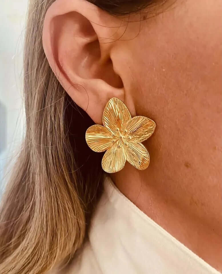 Worn as a stud, Love Language Earrings show their gold flower shape resting boldly at the earlobe.
