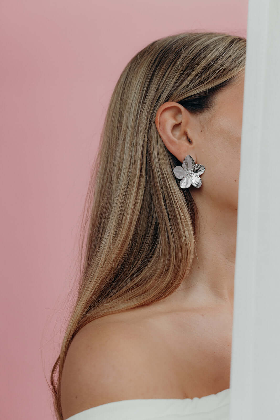 In silver tone, Love Language Earrings display their textured flower petals along the earlobe.