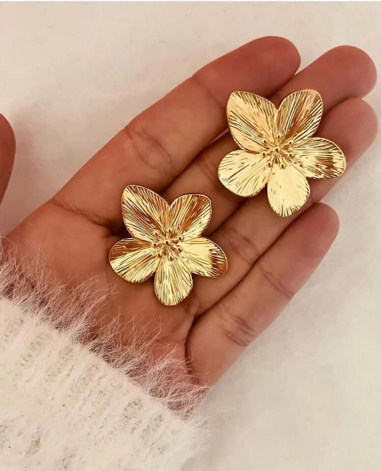 Held in hand, Love Language Earrings reveal the fine ridged texture of their gold flower petals up close.